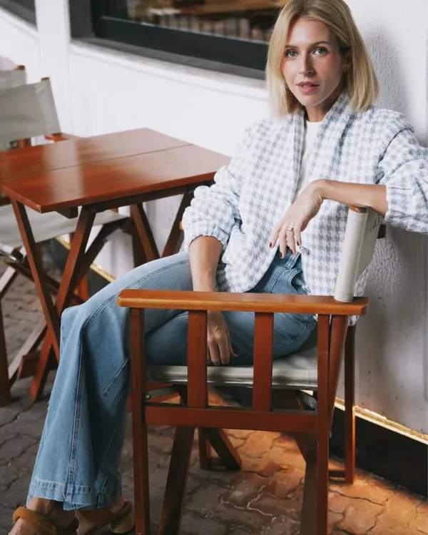Model wearing a checked shirt and flared jeans, seated at a café table