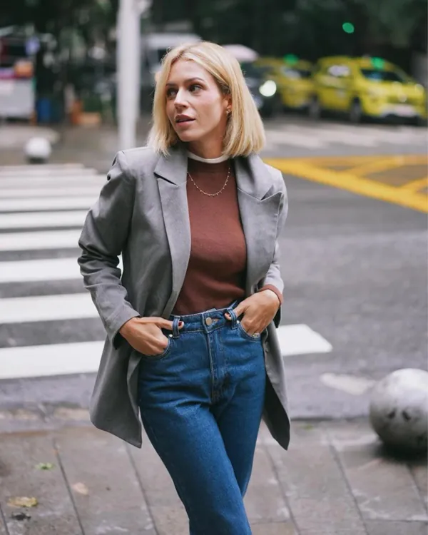 Model wearing a grey blazer, brown top and jeans on a crosswalk